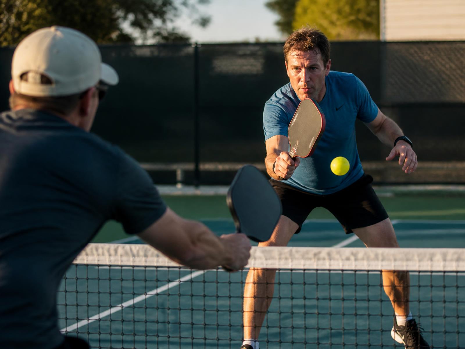 Two pickleball players trading dinks at the net on an outdoor court